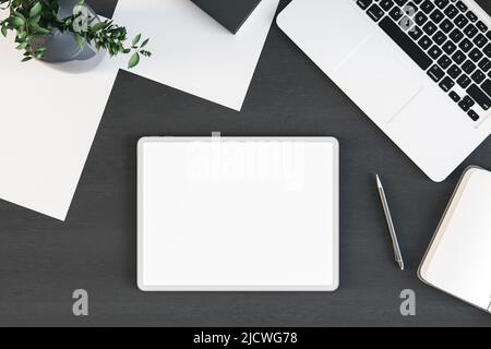 Vista dall'alto sullo schermo bianco bianco bianco bianco bianco del tablet digitale con superficie del tavolo in legno nero con notebook, piante verdi e fogli di carta. 3D rendering, simulazione Foto Stock