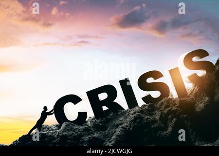 Crisi e problema personale concetto con l'uomo cercando di ottenere grande segno crisi sulla roccia al tramonto sfondo Foto Stock