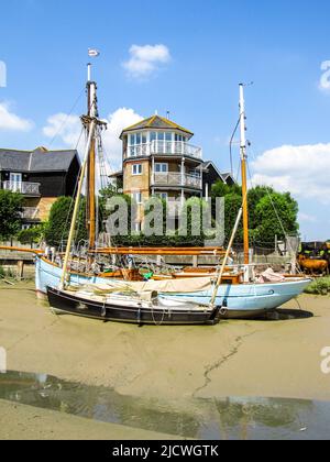 Barche a vela, ormeggiate su una barra di sabbia a bassa marea, con le case della città di Faversham sullo sfondo in una giornata estiva soleggiata Foto Stock