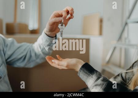 Felice giovane coppia che acquista la loro nuova casa e ricevere chiavi da agente immobiliare, primo piano Foto Stock