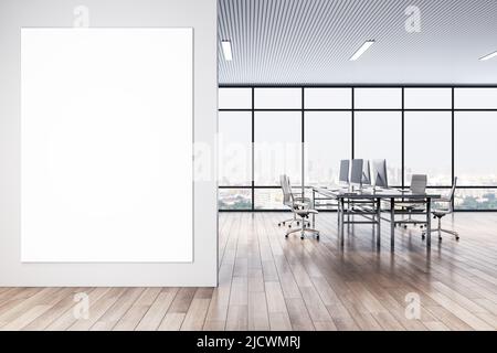 Vista frontale su un grande poster bianco sulla parete luminosa all'ingresso dello spazioso ufficio con vista della città dalla grande finestra e da eleganti posti di lavoro Foto Stock