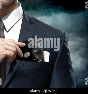 Uomo d'affari che prende una maschera in tasca. Ipocrisia. Maschera che simboleggia il bene e il male. Foto Stock