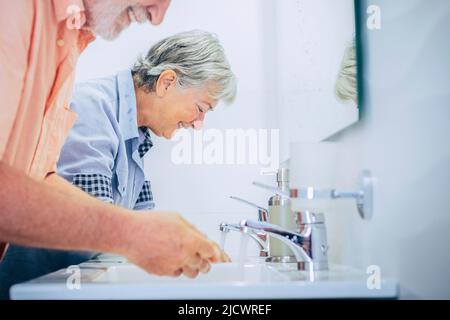 Coppia di uomo anziano e donna lavaggio ahnds a casa in bagno per prepararsi al mattino. Igiene e cura libera pensionati concetto lif Foto Stock