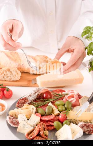 Donna che mangia antipasti italiani. Piatto di salumi con diversi tipi di salsicce e formaggi - salame, bresaola, prosuzzo, dorblu, parmigiano Foto Stock