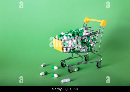 Carrello con pillole mediche su sfondo verde Foto Stock