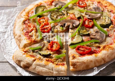 Pizza vegetariana con zucchine, pomodoro, peperoni e funghi su tavola di legno Foto Stock