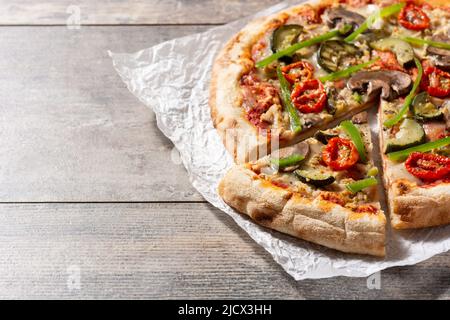 Pizza vegetariana con zucchine, pomodoro, peperoni e funghi su tavola di legno Foto Stock