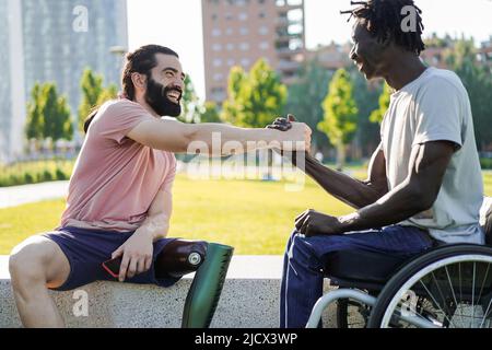 Amici multietnici con disabilità si salutano a Park City - Focus su protesi gamba Foto Stock