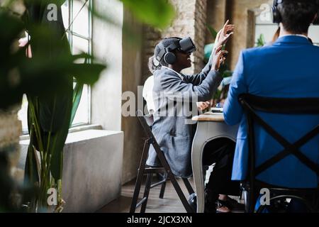 Uomini d'affari multietnici che indossano occhiali vr all'interno dell'ufficio - concentrarsi sulle mani degli uomini anziani Foto Stock
