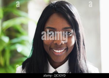 Felice donna d'affari africana che lavora all'interno di un ufficio moderno - Focus on Face Foto Stock