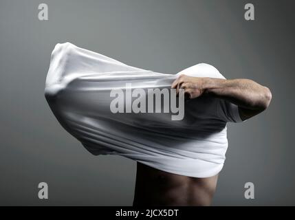 Uomo che lotta per mettere su camicia Foto Stock