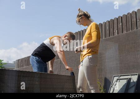 Coppia che ha difficoltà nel montaggio di mobili, la creazione e la preparazione di divano per la vita terrazza in casa cittadina Foto Stock