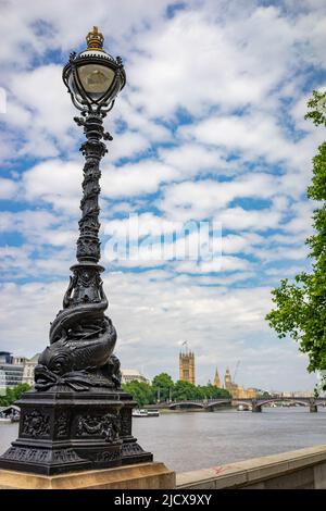 Gli standard per lampade Dolphin forniscono luce elettrica lungo gran parte del Thames Embankment a Londra, Regno Unito. Due delfini stilizzati o stangeoni si fanno da brividi Foto Stock