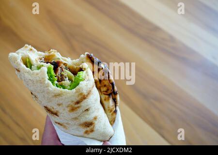 Biten meatball wrap in man mano da vicino vista con copyspace Foto Stock