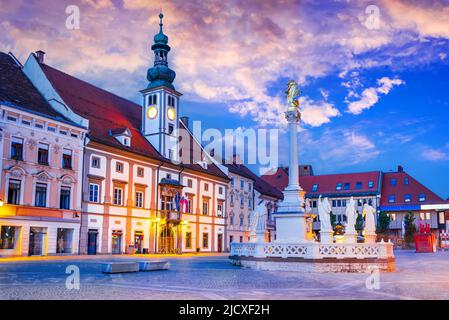 Maribor, Slovenia. Piazza principale colorata al crepuscolo con colonna peste, spot da viaggio sloveno. Foto Stock