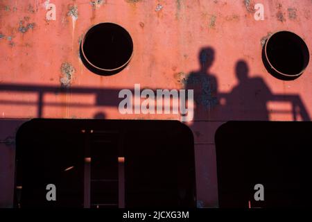 Ombra sfocata di due persone sulla superficie di una grande struttura di ingegneria metallica. Foto Stock