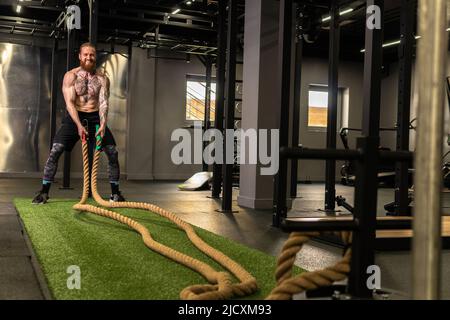 Corda magazzino fitness uomo verde erba palestra muscolare giovane, per la forza forte da attività fisica sana, muscolare persona. Croce Foto Stock