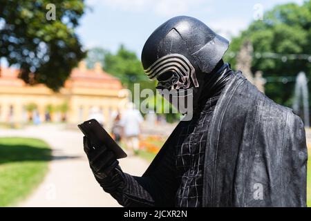 Erlangen, Germania. 16th giugno 2022. Cospayer Frank, qui in costume come personaggio di Star Wars Kylo Ren, guarda il suo smartphone mentre visita il Salone Comic 2022 di Erlangen. Credit: Nicolas Armer/dpa/Alamy Live News Foto Stock