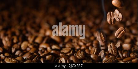I chicchi di caffè arrostiti marroni si avvicinano su sfondo scuro Foto Stock