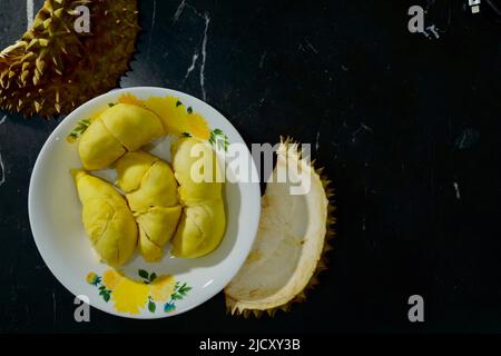 Durian fresco in confezione su piatto bianco con buccia dura su sfondo nero banner. Durian re di frutta. Frutta tropicale. Vista dall'alto di durian maturo, WO Foto Stock