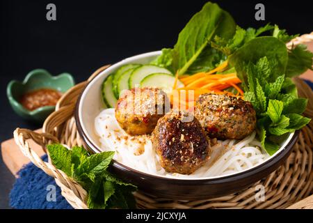 Concetto di cibo Bun Cha spaghetti di riso vietnamiti e polpette di carne con verdure ed erbe su sfondo nero con spazio copia Foto Stock