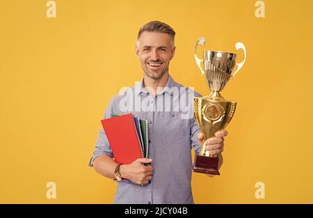 il ragazzo celebra la vittoria, l'ispirazione e la motivazione. l'uomo maturo felice tiene la tazza d'oro Foto Stock