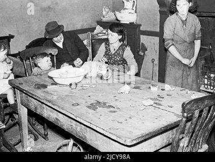 1940s, storico, post-ww2, familiari femminili, giovani e anziani, Seduti intorno a un tavolo di legno e fuoco reale in una piccola stanza all'interno di una casa nel villaggio minerario di Trehafod, Galles del Sud, Regno Unito. Foto Stock