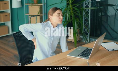 Office Syndrome.Woman cercando di alzarsi dal tavolo improvvisamente sensazione di dolore in Back.Woman sensazione stanca di lungo stile di vita sedentario cercare di rilassarsi e R Foto Stock