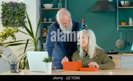 Una coppia anziana felice che celebra il compleanno in linea che ha divertimento che gode del Internet Foto Stock