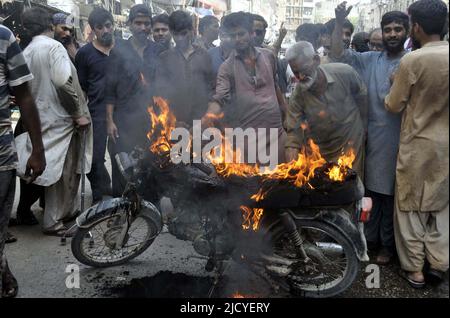 I membri di Anjuman-e-Tahafuz Dukandar stanno bruciando la motocicletta mentre stanno tenendo la dimostrazione di protesta contro l'aumento di prezzo dei prodotti petroliferi, fuori Qadam GHA Mola Ali (A.S) a Hyderabad giovedì 16 giugno 2022. Foto Stock