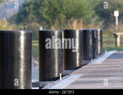 palafitte nere sul molo per allacciare le barche il canale con gli alberi sullo sfondo Foto Stock