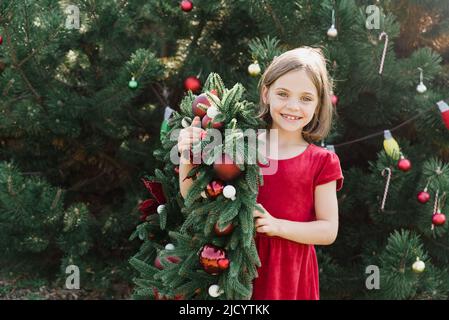 Buon Natale. Ritratto delle ragazze divertenti felici del bambino in Santa cappello con la corona di Natale. Buone feste. Magia delle fate. Buon bambino che si gode la vacanza. Natale nel mese di luglio Foto Stock