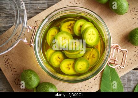 Macerando noci non mature in alcol in un vaso, per preparare tintura fatta in casa o liquore di noci, vista dall'alto Foto Stock