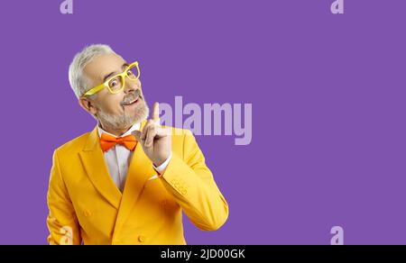 Ottima idea. Allegro uomo caucasico di mezza età che punta il dito su con ispirazione, sfondo giallo. Spazio per la vostra pubblicità. Foto Stock