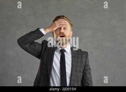 L'uomo d'affari schiaffe di mano sulla fronte mentre si rende conto che ha fatto un errore o dimenticato qualcosa Foto Stock