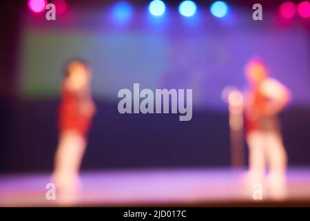 Silhouette di piccoli ballerini di due persone. Sfondo sfocato colorato del festival di danza. Illuminazione palcoscenico brillante. Foto di alta qualità Foto Stock