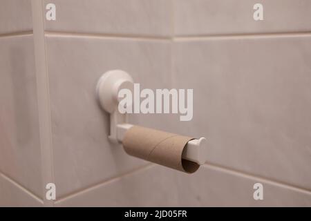 Rotolo di carta igienica vuoto sul supporto carta igienica. WC, toilette, toilette e bagno dettaglio. Messa a fuoco e profondità di campo molto poco profondi. Foto Stock