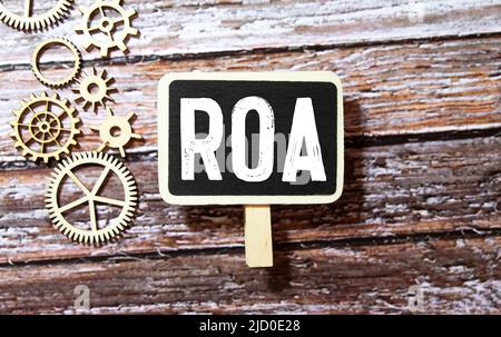 Lettera alfabetica in parola ROA Abbreviazione di ritorno su beni su sfondo legno. Foto Stock