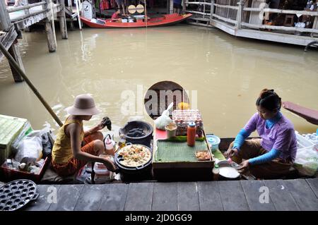 I venditori thailandesi preparano i pasti tradizionali sulla sua barca al mercato galleggiante - Pattaya, Tailandia. Foto Stock