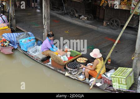 I venditori thailandesi preparano i pasti tradizionali sulla sua barca al mercato galleggiante - Pattaya, Tailandia. Foto Stock