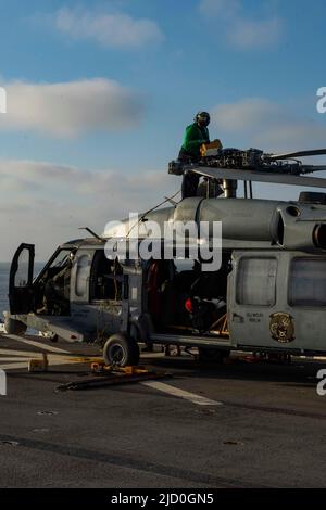 OCEANO PACIFICO (15 giugno 2022) Aviation Electrician’s Mate 2nd Classe Nikisha Anderson, nativo di Lich, Germania, assegnato a Helicopter Sea Combat Squadron (HSC) 8, piega manualmente i rotori di un elicottero MH-60s Sea Hawk a bordo di una nave d’assalto anfibio USS Essex (LHD 2) 15 giugno 2022. Essex sta conducendo operazioni di routine nella flotta USA 3rd. (STATI UNITI Foto della Marina di Seaman Donita Burks, specialista della comunicazione di massa) Foto Stock