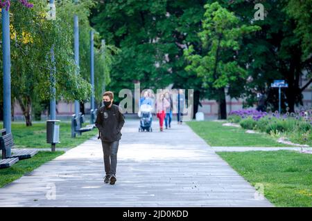 Foto di un giovane ragazzo bianco caucasico che cammina per le strade di Belgrado, Serbia, indossando una maschera protettiva, durante il 2020 2021 Foto Stock