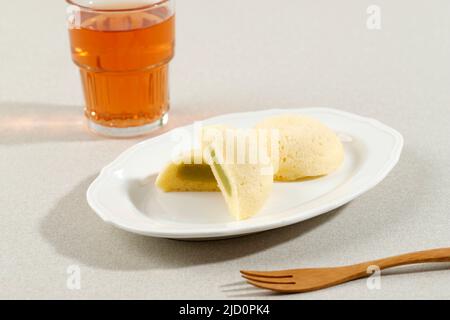 Bakpia Kukus Kacang Hijau, mini torta al vapore con ripieno di fagioli mung, servita con tè. Foto Stock