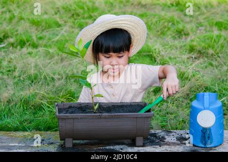 La bambina che indossa un cappello aiuta la madre nel giardino, un piccolo giardiniere. Cute ragazza piantando fiori in pentole per la vendita. Famiglia piccola impresa Foto Stock