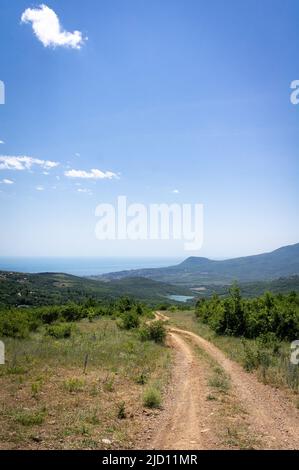 Un paesaggio tranquillo con la strada che va in lontananza. Estate in montagna, mare e sole. Il concetto di turismo, ricreazione. Foto verticale. Foto Stock