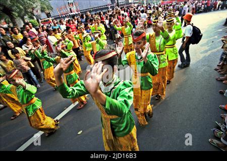 Giovani donne che si esibiscono in una danza tradizionale partecipando a una sfilata durante il Carnevale di Giacarta 2004 nel centro di Jakarta, Jakarta, Indonesia. Foto Stock