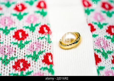 Da vicino ai bottoni giramonzoli rosa e rosso del maglione in oro perla sulla parte superiore del maglione tshirt. Foto Stock
