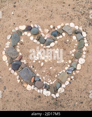 Conchiglie a forma di cuore e ciottoli su una spiaggia. Scozia Foto Stock