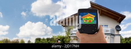 Close-up di persona a rilevare la perdita di calore al di fuori di casa usando la termocamera infrarossa Foto Stock