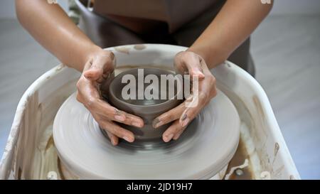 Immagine ritagliata, le mani della donna modellano argilla, facendo una ceramica di argilla nell'officina artigianale. Concetto di produzione artigianale Foto Stock